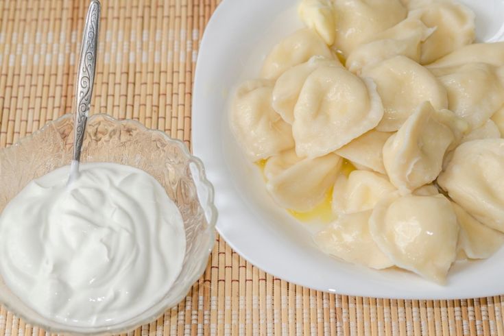 a bowl of dumplings next to a small bowl of yogurt