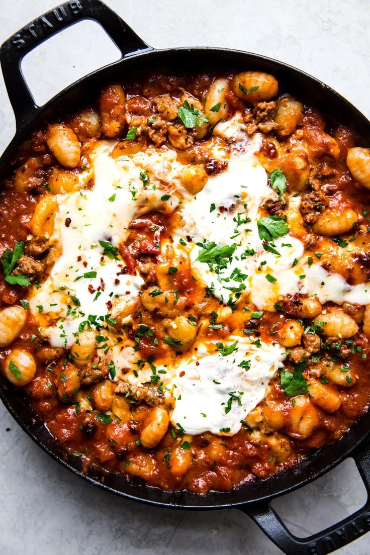 a skillet filled with chickpeas and cheese on top of a white table