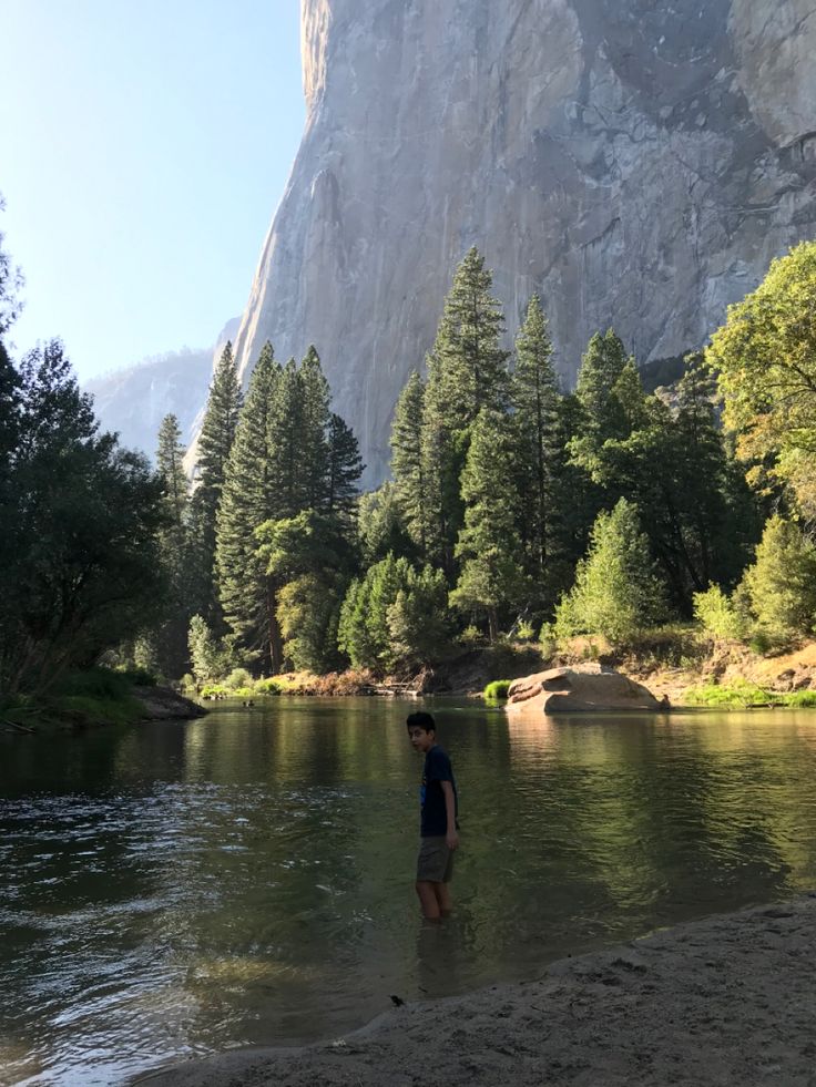 a person standing in the water next to a mountain