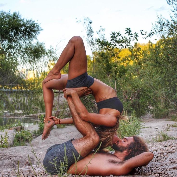 two people are doing acrobatic tricks on the ground in front of some trees