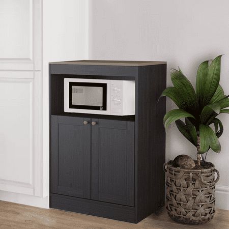 a microwave oven sitting on top of a cabinet next to a potted plant