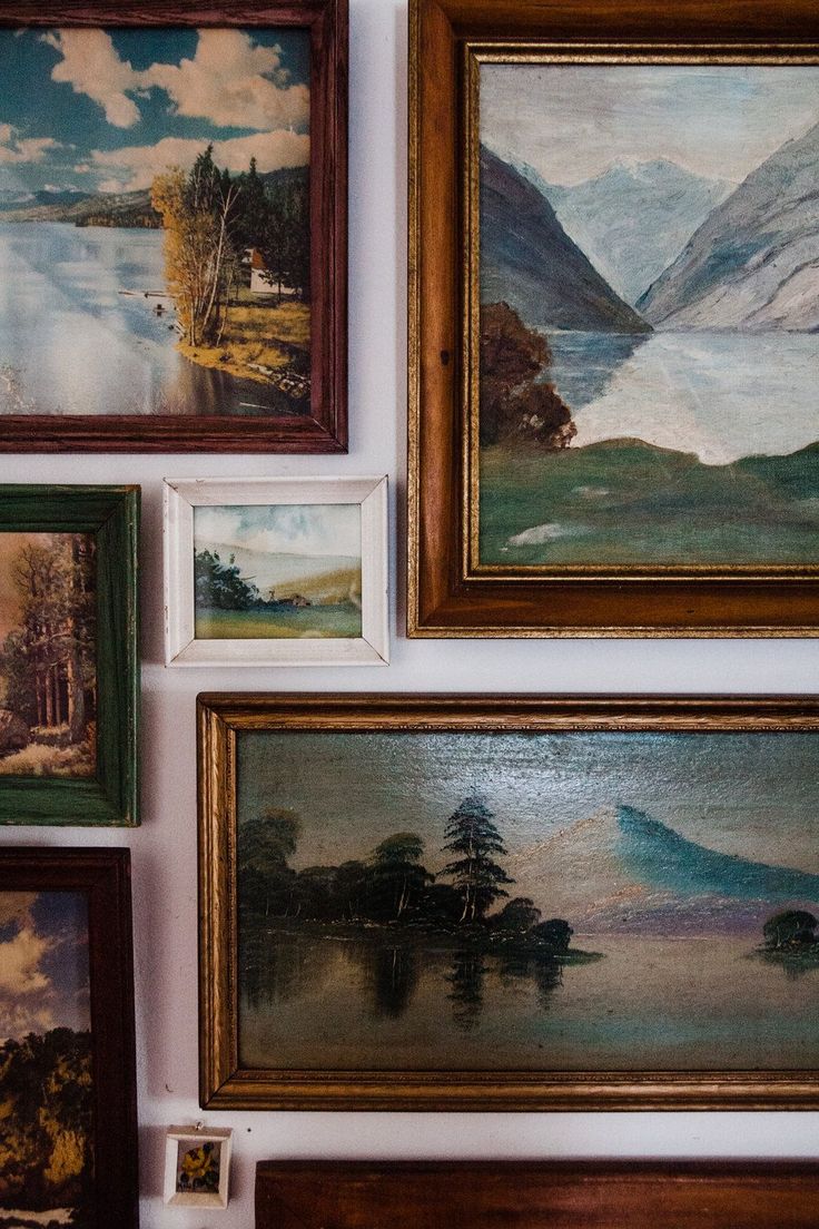 many paintings are hanging on the wall near each other