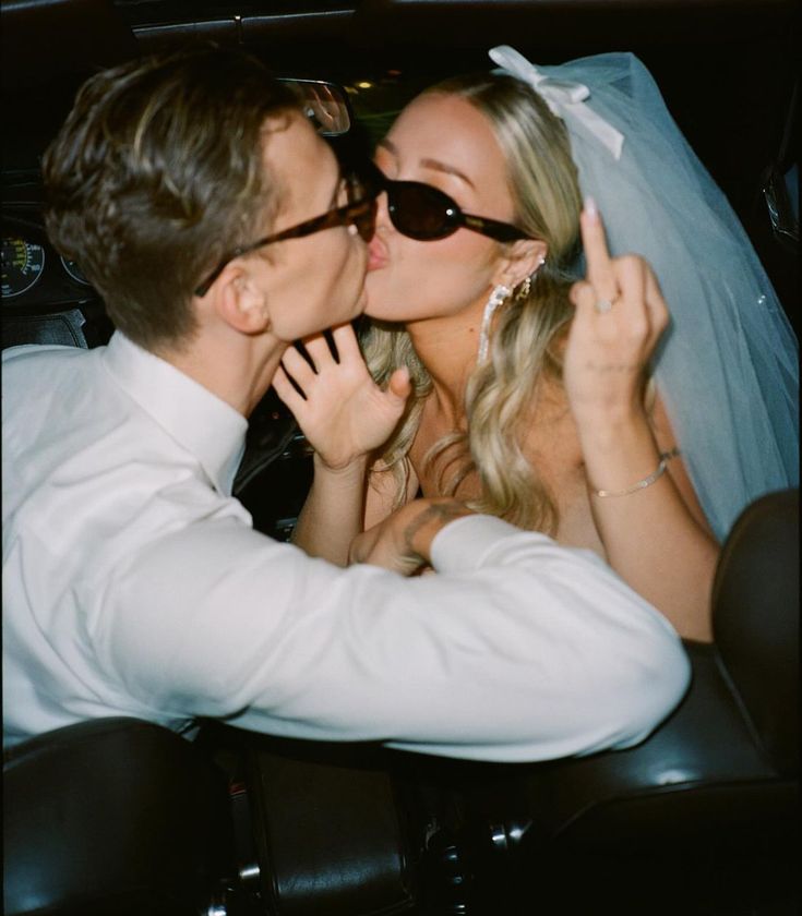 a bride and groom kissing in the back seat of a car on their wedding day