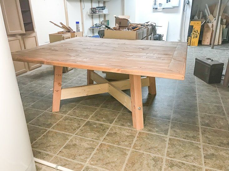 a wooden table sitting in the middle of a room with tile flooring and walls