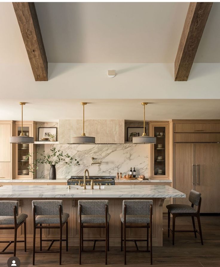 a kitchen with marble counter tops and wooden beams on the ceiling, along with four bar stools