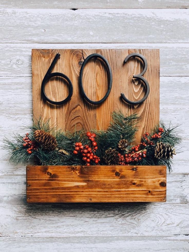 a wooden box with pine cones, berries and evergreens in it on a white wood background