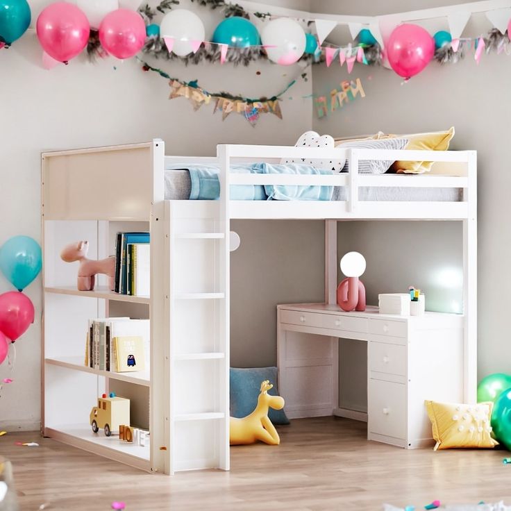 there is a loft bed with a desk underneath it and balloons hanging from the ceiling