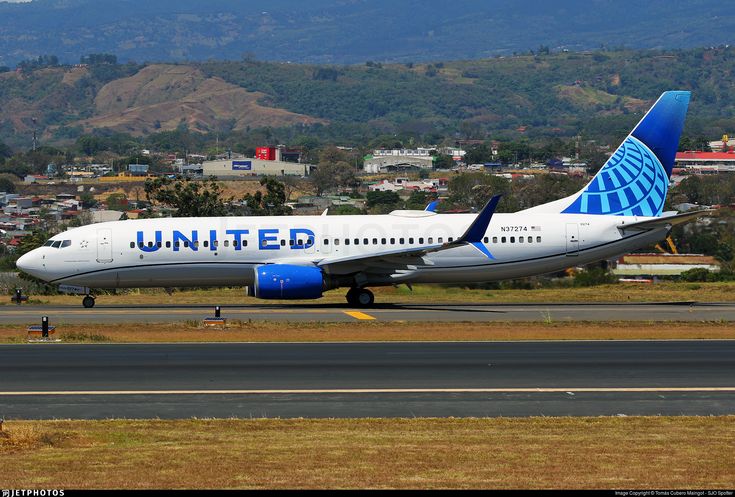 an airplane on the runway with mountains in the background