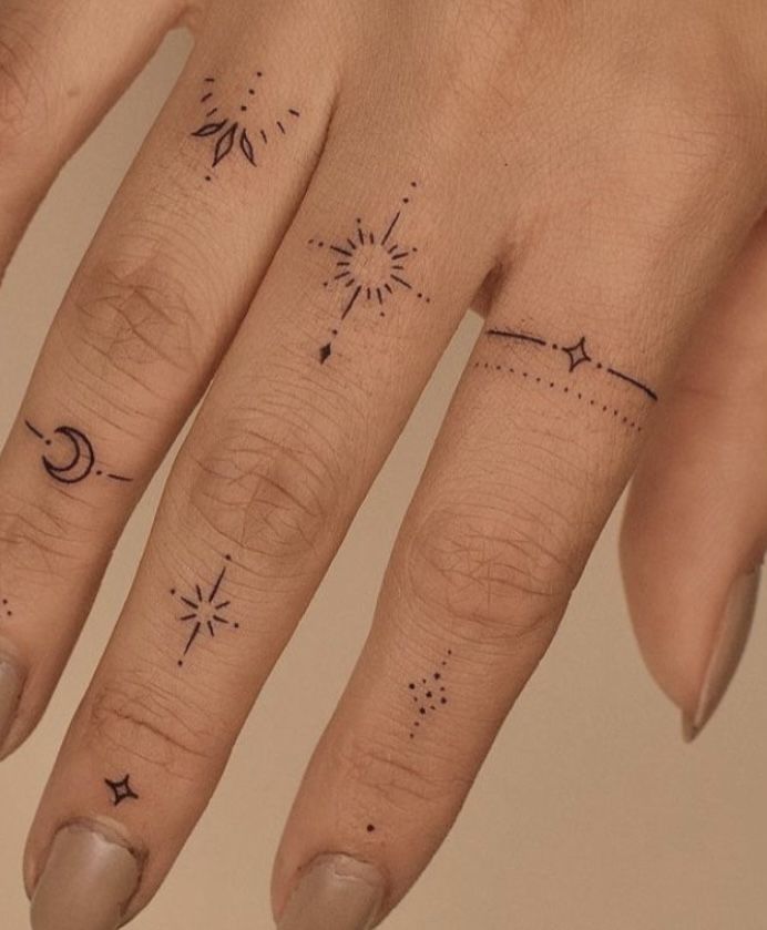 a woman's hand with tattoos on it and a star and moon tattoo on the middle finger