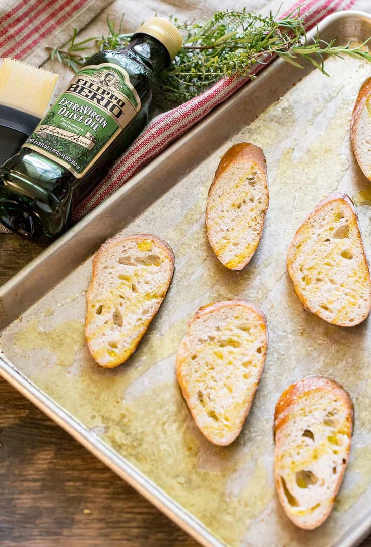 an image of bread on a baking sheet with herbs and olives in the background