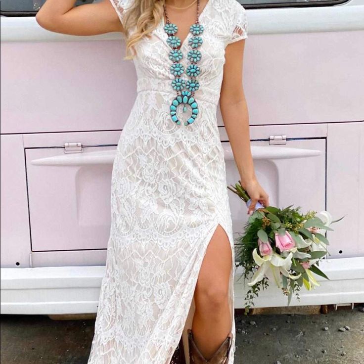 a woman in a white dress and cowboy hat leaning against a van with flowers on it