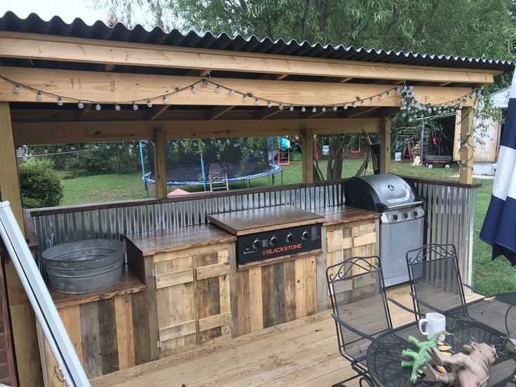 an outdoor bbq with grill, table and chairs