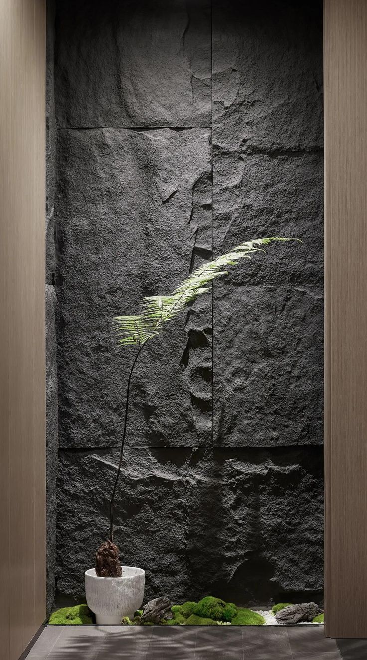 a black stone wall with a plant in it