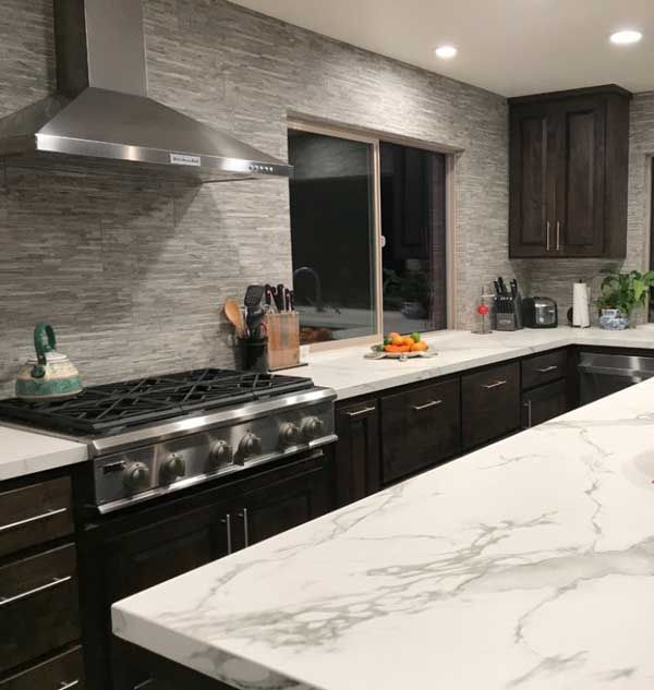 a kitchen with marble counter tops and dark wood cabinets, along with stainless steel appliances