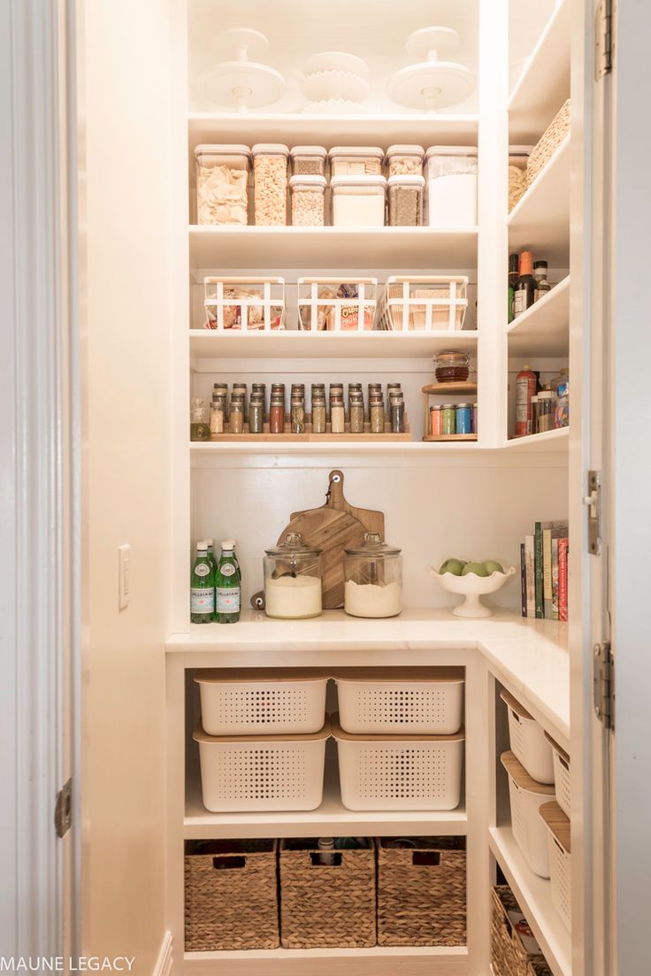 an organized pantry with white shelves and baskets