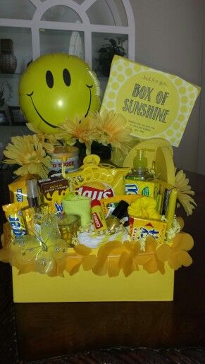 a yellow box filled with lots of goodies and a smiley face balloon in it