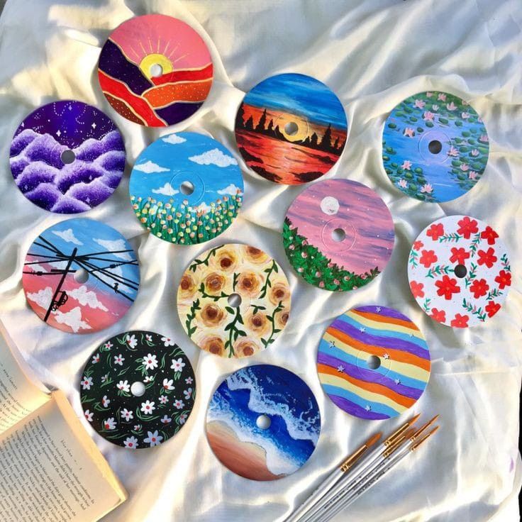 a table topped with lots of different types of painted buttons next to an open book