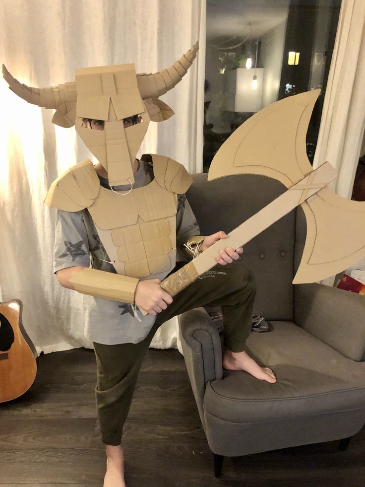 a person sitting on a couch with a cardboard costume made to look like a dragon