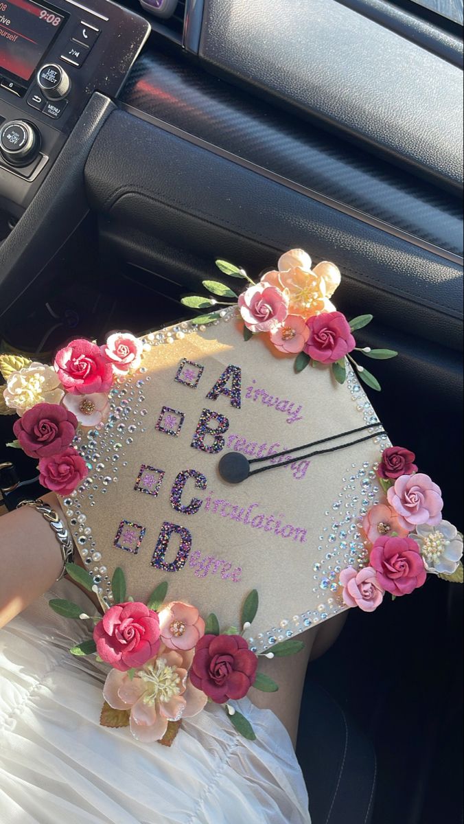 a decorated graduation cap sitting on the dashboard of a car with flowers and beads around it