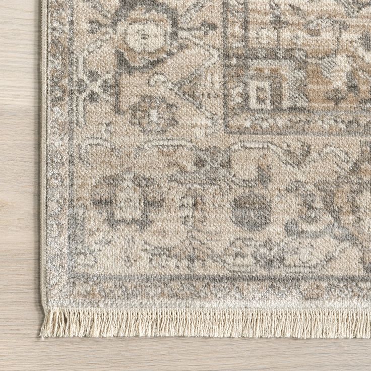 an area rug with fringes on top of it and a wooden floor in the background