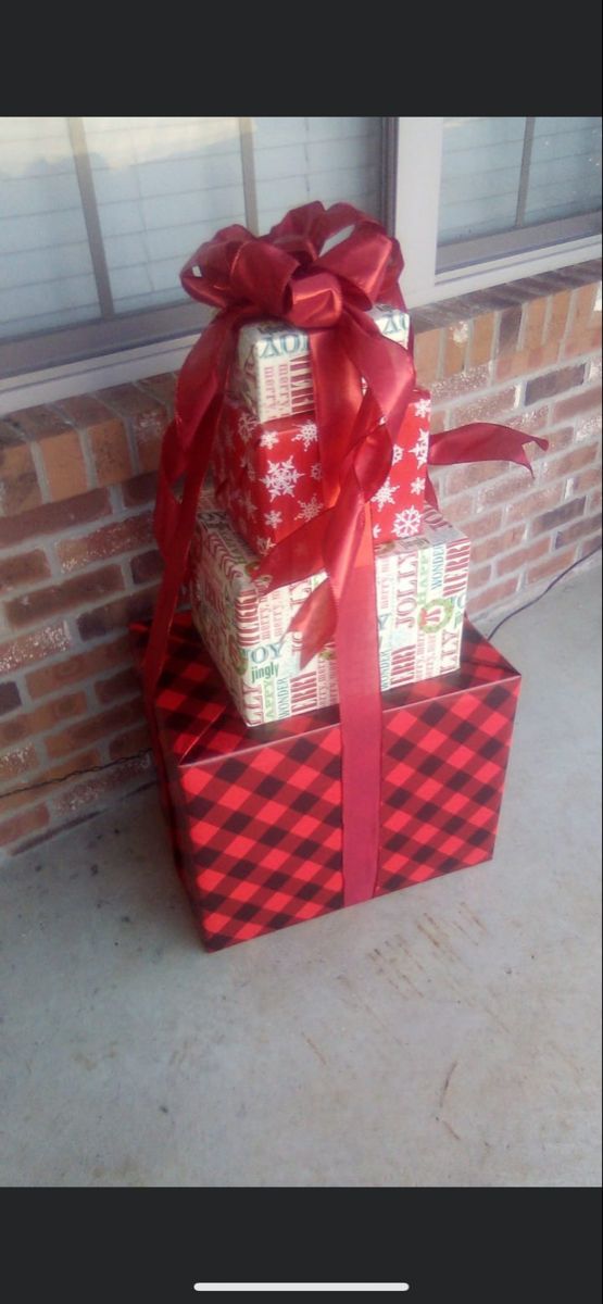 three wrapped presents sitting on top of each other in front of a brick wall and window