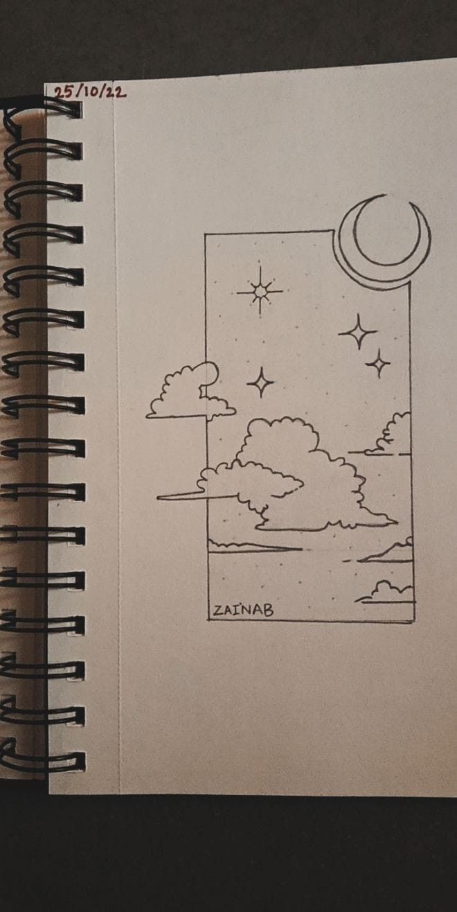 an open notebook with a drawing of the moon and stars above it on top of a table