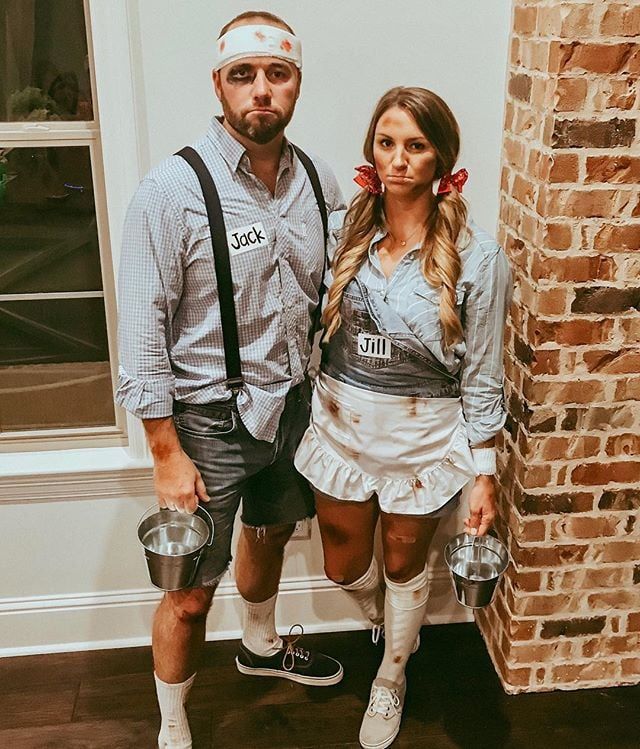 a man and woman dressed up in costumes standing next to each other near a brick wall