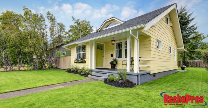 a small yellow house sitting on top of a lush green field