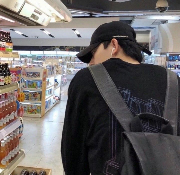 a man with a backpack is looking at the shelves in a grocery store that sells drinks