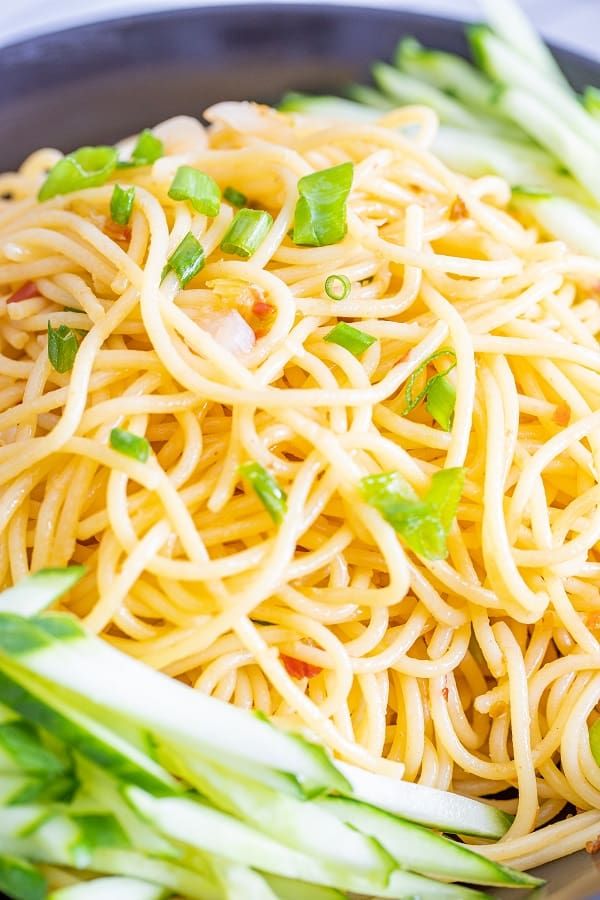 a bowl filled with noodles and asparagus on top of a table