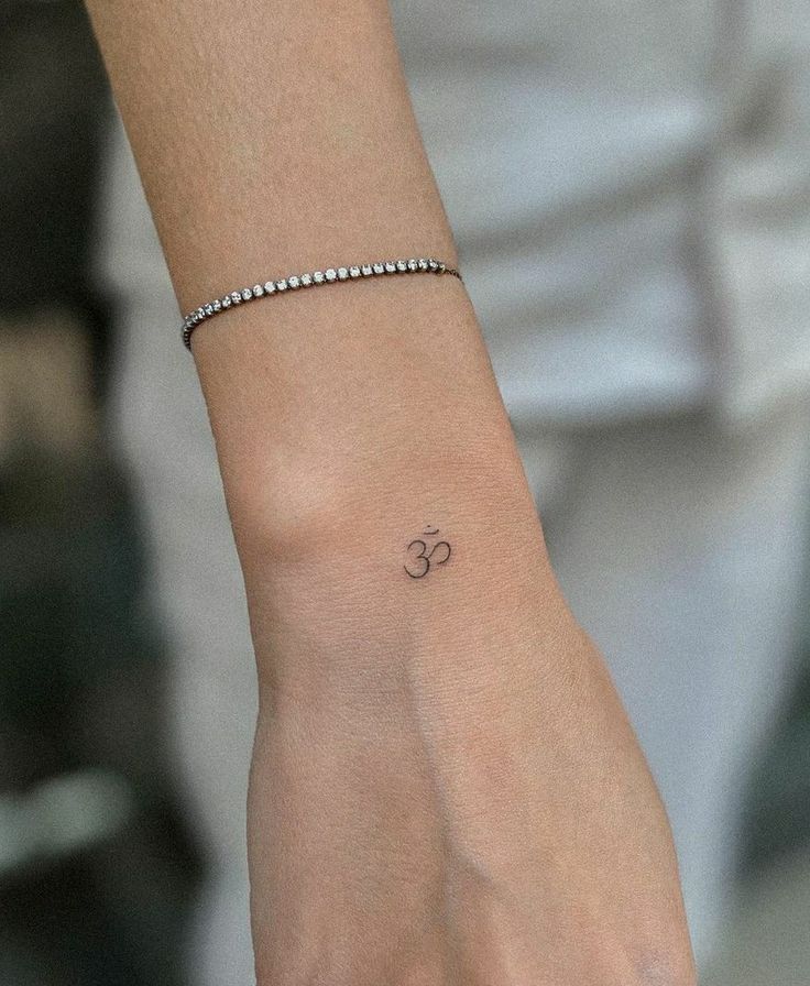 a woman's wrist with an om symbol tattoo on the left side of her arm