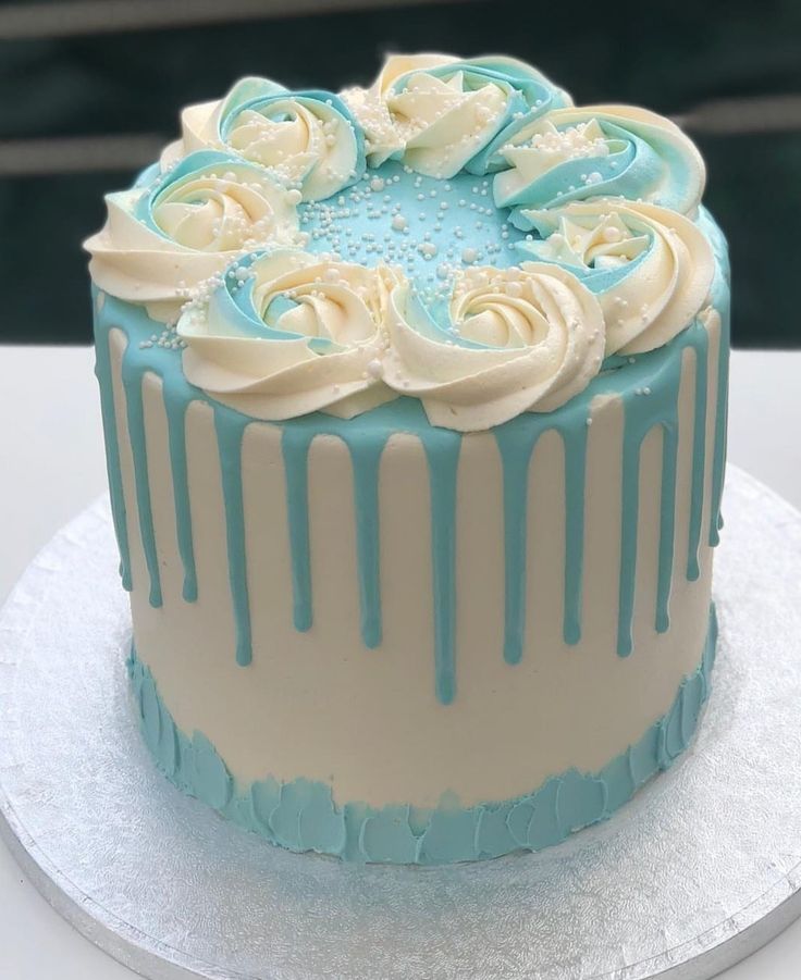 a blue and white frosted cake with icing on it's top sitting on a table