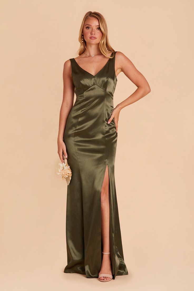 a woman in a long green dress with a slit down the side and her hand on her hip