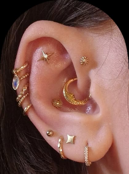 a woman wearing gold ear piercings with stars and moon designs