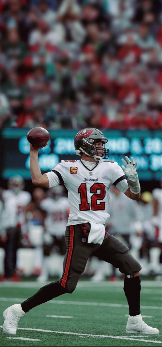 a man throwing a football on top of a field with a crowd in the background