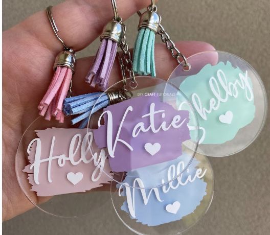 four key chains with tassels on them in the shape of hearts and words