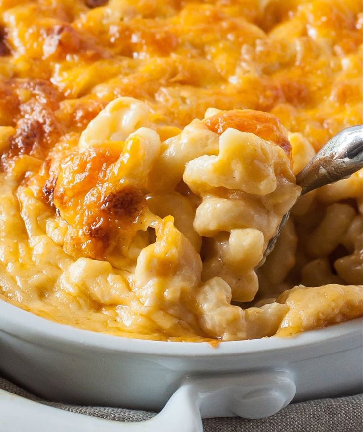 macaroni and cheese is being spooned into the casserole in a white dish