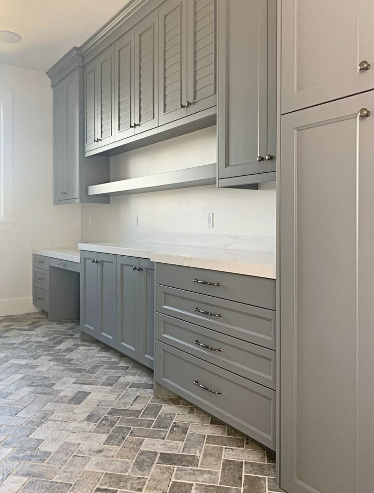 a kitchen with gray cabinets and tile flooring