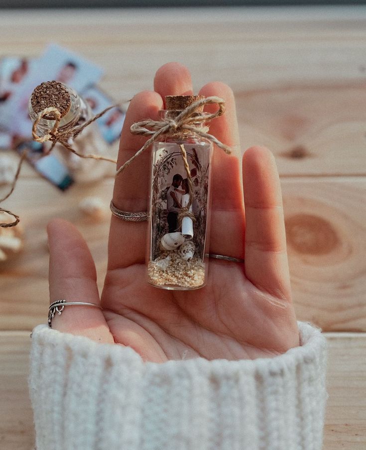 a person holding a tiny glass bottle in their hand with some string attached to it