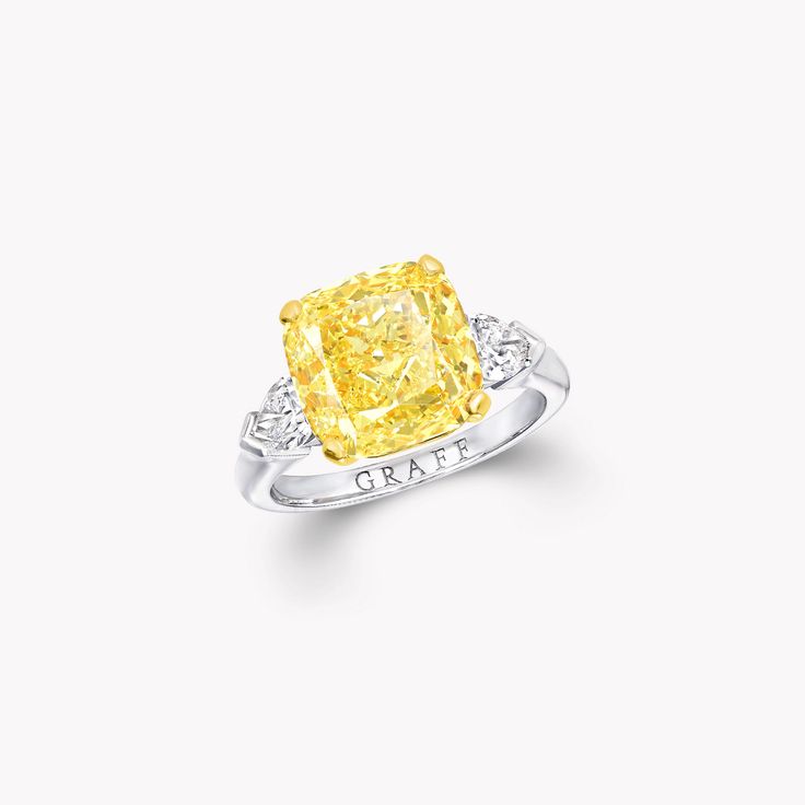 a yellow diamond ring with two diamonds on the sides and an inscription in white gold