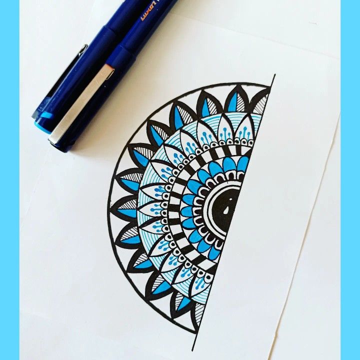 a blue and black design on a piece of paper next to a marker with a pen