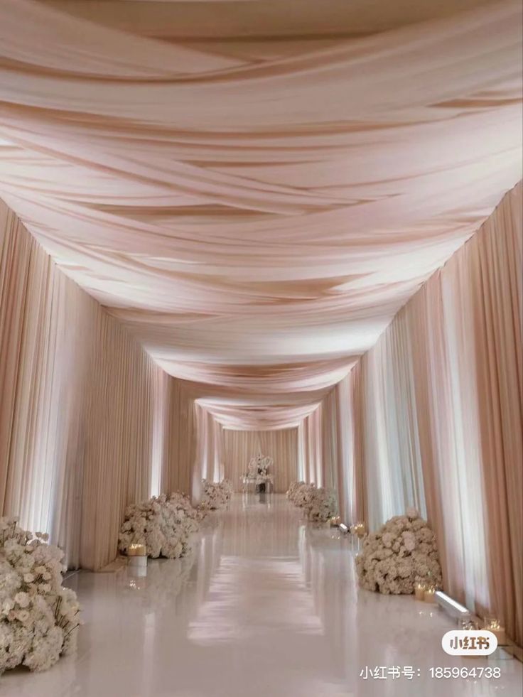 an aisle with white flowers and draping on the sides is shown in this image