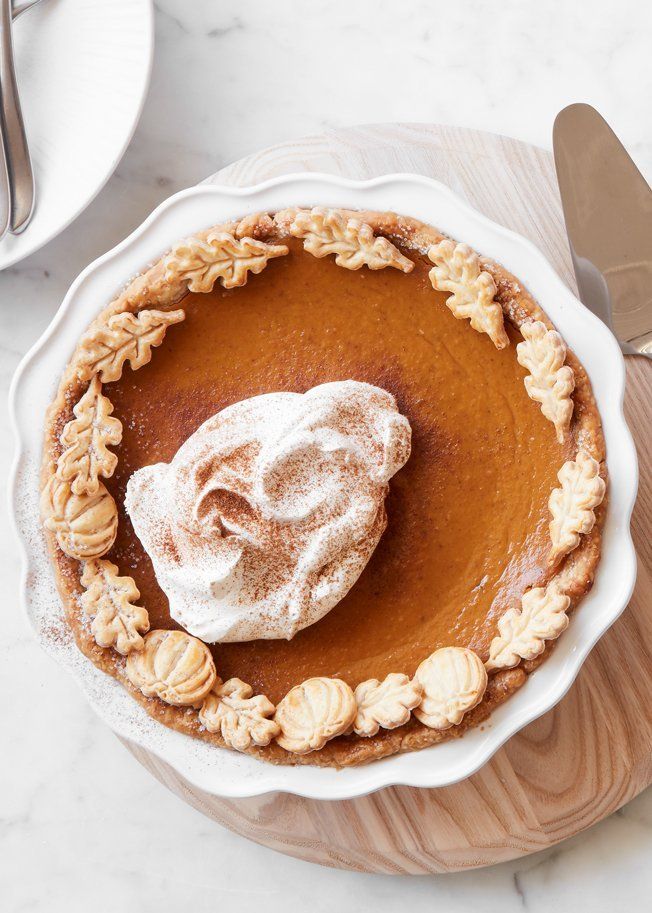 a pumpkin pie with whipped cream on top and some silverware next to it,