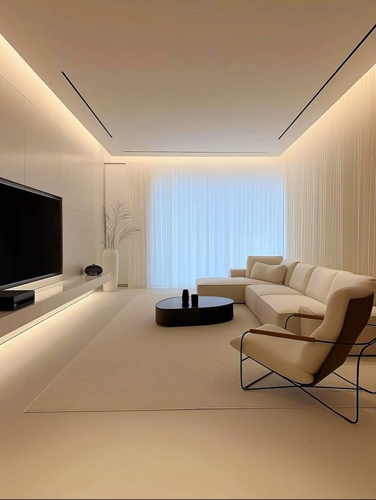 a modern living room with white walls and beige furniture, along with a large flat screen tv mounted on the wall