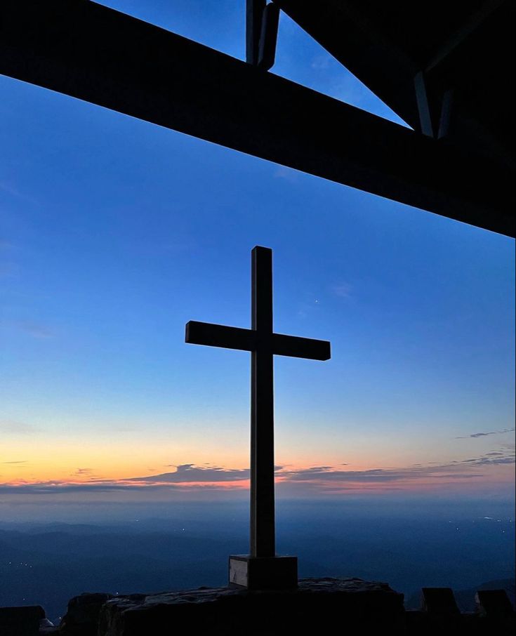 a cross on top of a hill at sunset