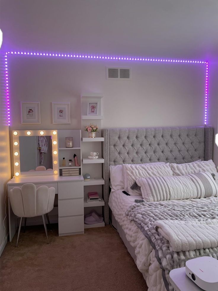 a bedroom with a bed, desk and vanity in it's corner area is lit up by purple lights