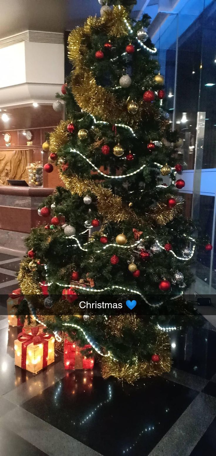 a christmas tree with presents under it in a lobby at the holiday inn, new york city