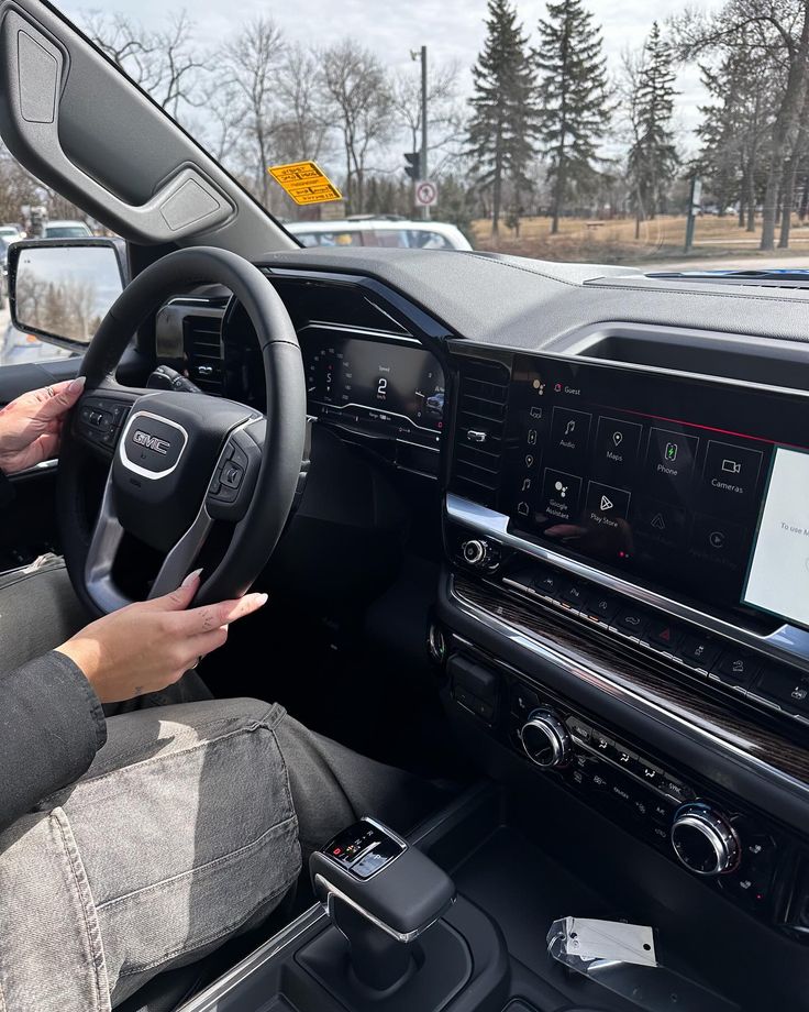 a person sitting in the driver's seat of a car with their hands on the steering wheel