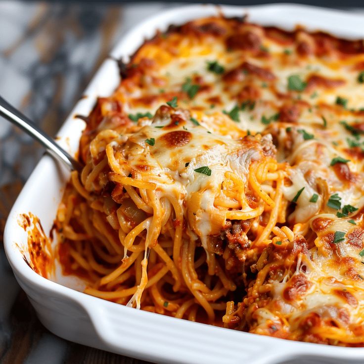 a white casserole dish filled with spaghetti and meat