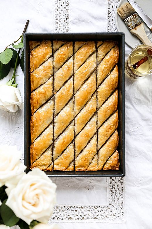 a pan filled with pastry sitting on top of a table next to flowers and utensils